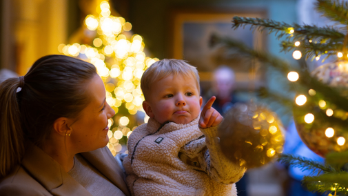 A mother and child enjoying a Christmas tree in the Hall of Tyntesfield House, Somerset